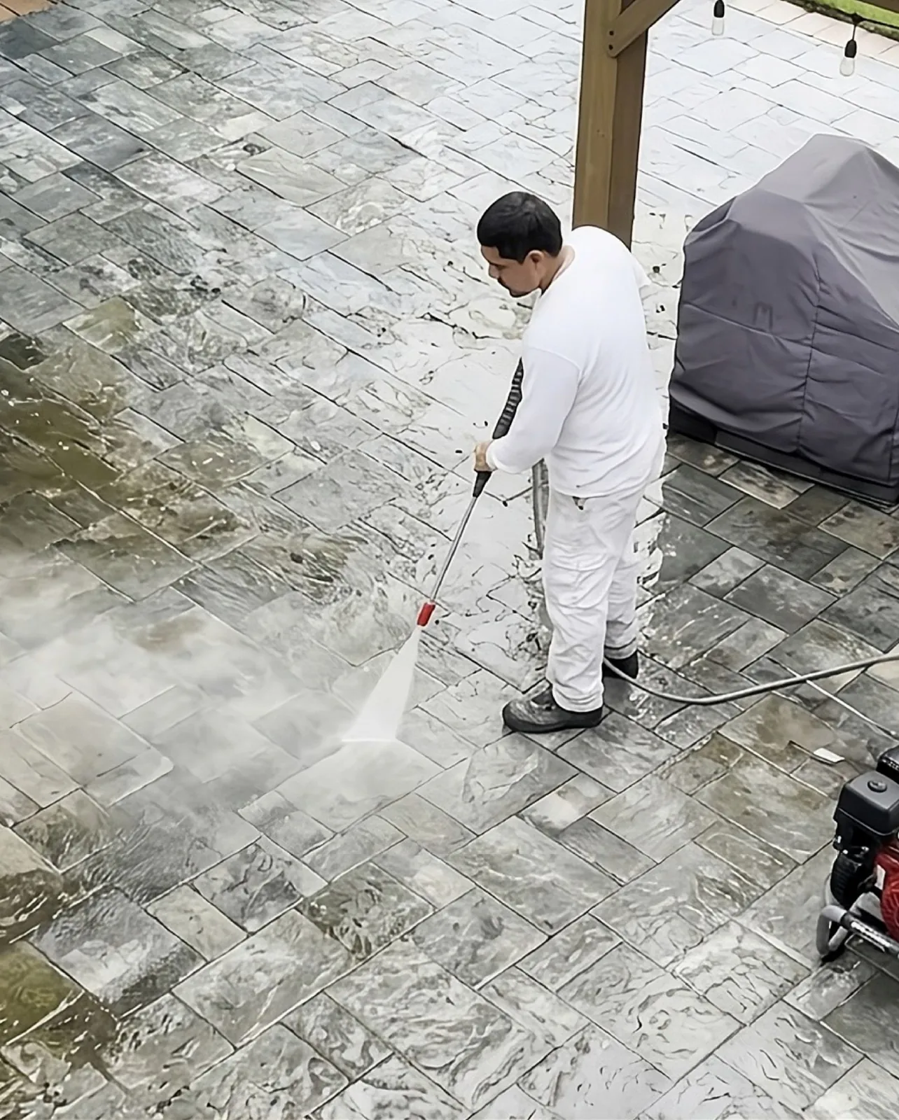 Power washing a patio back to clean stone